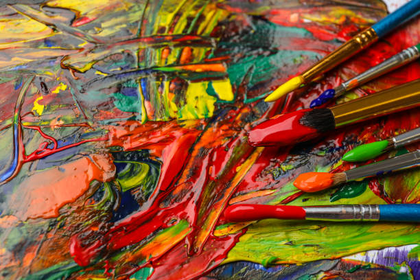istock Set of brushes with different paints on artwork, closeup 1380711456