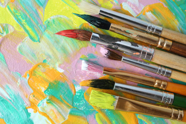 istock Set of different brushes on abstract colorful paint, flat lay 1380711470