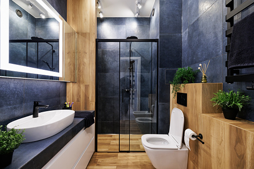 Modern, dark luxury bathroom with indigo and wood like tiles. Black rain shower head. Lacquered white drawers. Modern mirror with built-in led illumination.\nCanon R5.