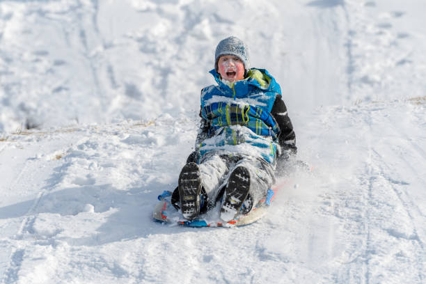 istock Snow-covered Boy Sledding Down Hill on Snow 1380728173