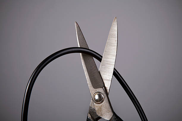 close up of metal scissors cutting black wire - kesmek stok fotoğraflar ve resimler