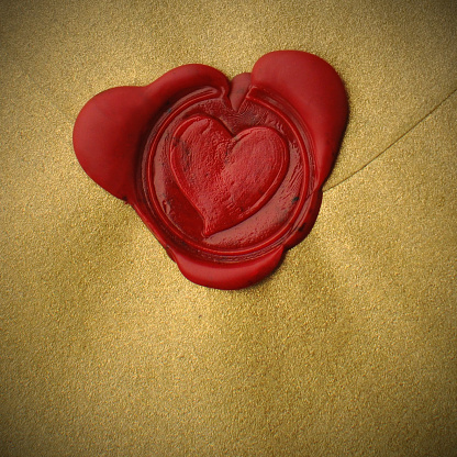 Close Up Red Wax Seal Heart Shape on Gold Envelope