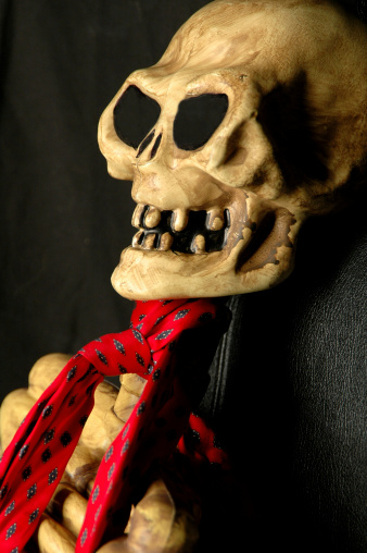 Skeleton with a necktie sitting in an office chair