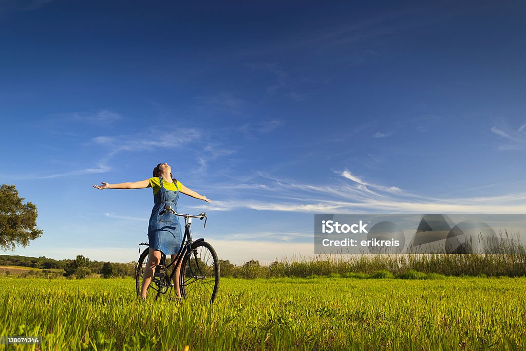 Enjoying the Spring Happy woman relaxing and sitting on a bicycle, in a green meadow Activity Stock Photo