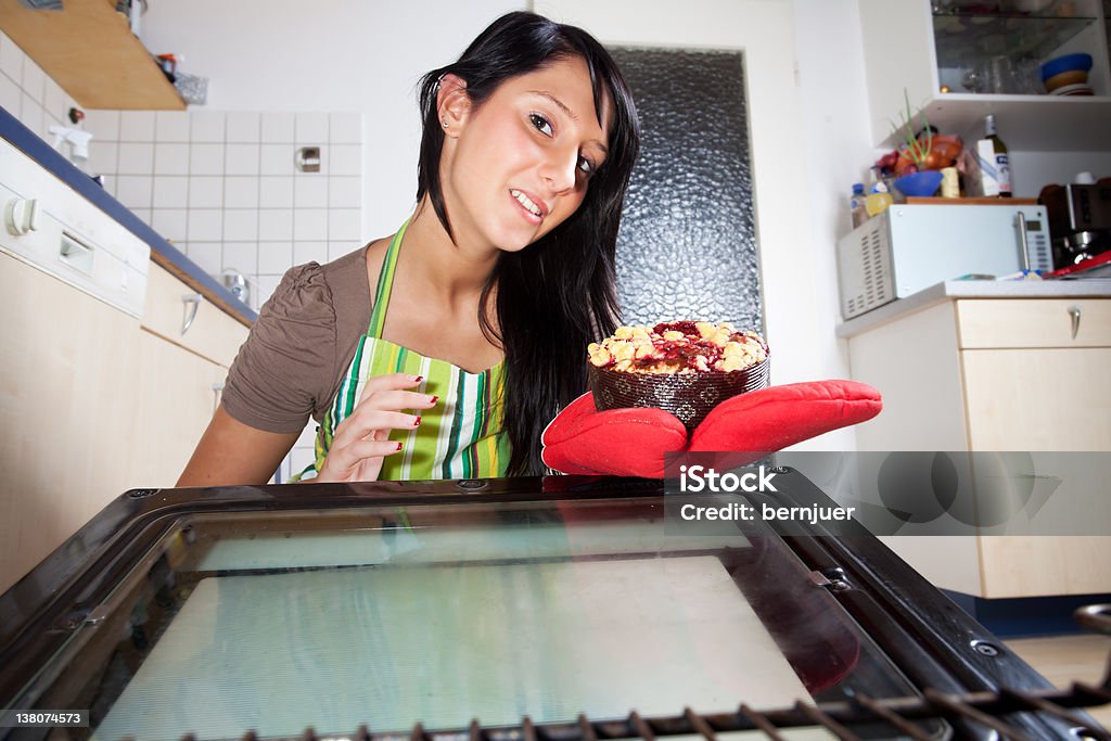 oven woman fetching a cake from an oven Adult Stock Photo