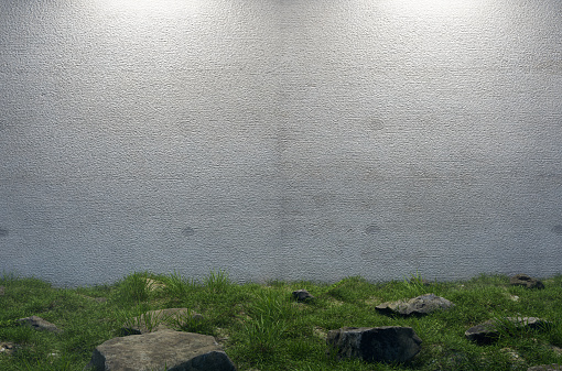 Mysterious Blank Cement Wall Surrounded by Large Rocks and Grass in Field.