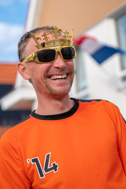 Dutch man in orange mock up shirt celebrates Koningsdag holiday event. Oranje Kings day man laughing stock photo