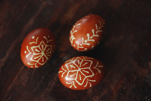 Hand made decorate Easter eggs on the dark table, painted in red with wax ornament