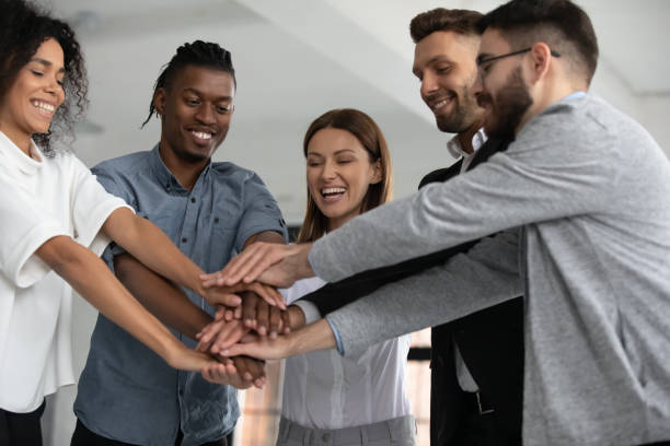 istock Excited diverse employees stack hands celebrate success 1380764386