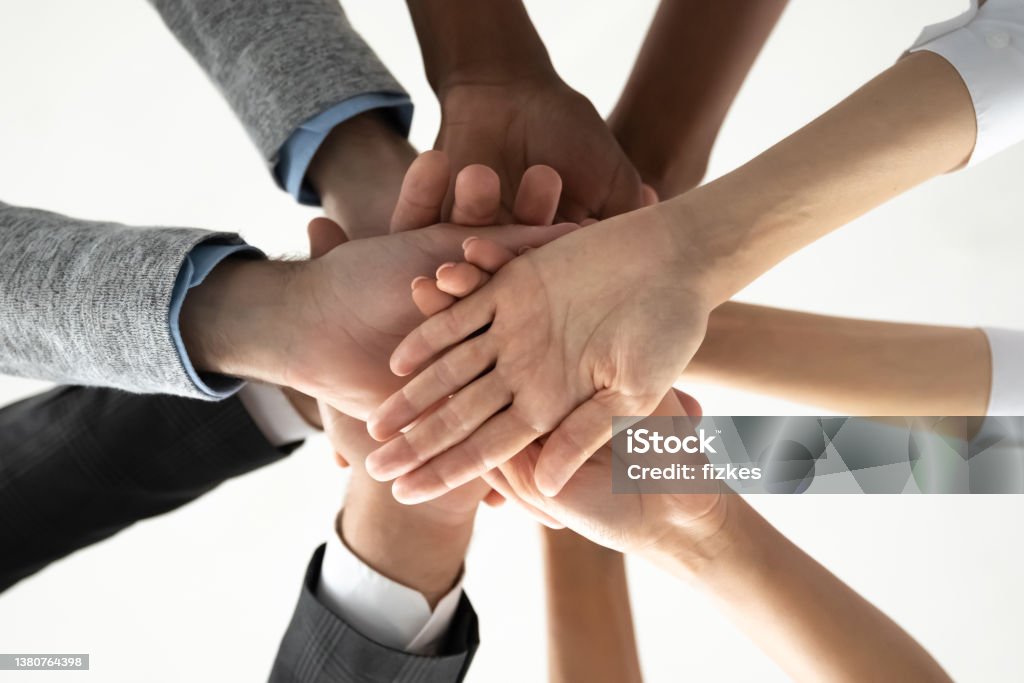 Close up of diverse people stack hands for shared success Crop close up of diverse international people join stack hands in pile motivated for shared team success or achievements. Multiethnic employees involved in teambuilding activity. Teamwork concept. Angle Stock Photo