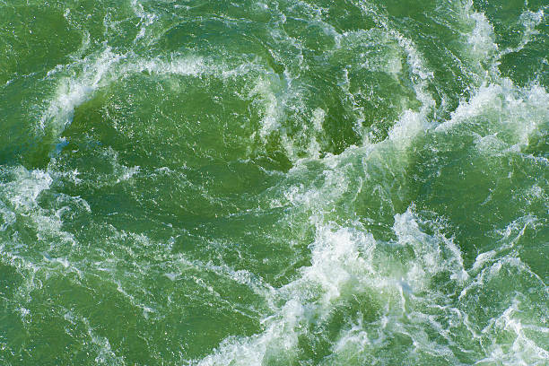 turbinio di acqua nella parte anteriore di un blocco - green sea whirlpool bubble foto e immagini stock