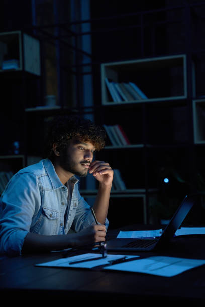 istock Focused young indian business man working online at night using laptop. 1380857523