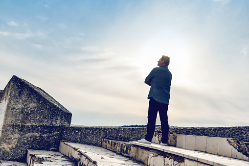 Senior Active Male Looking at the Sky Hopping for Better Future and Leaving the ruins of the city behind.