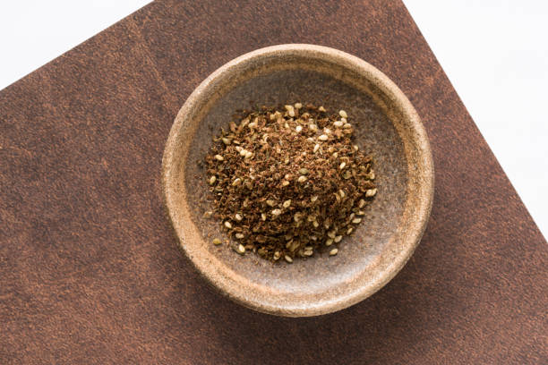 Raw Organic MIddle Eastern Zaatar Spices in a jar on white backgroud isolated. Za'atar is a culinary herb or family of herbs. It is also the name of a spice mixture that includes the herb along with toasted sesame seeds, dried sumac and salt