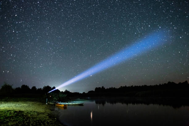 istock Silhouette of man on dark background. Light beam from flashlight. Summer starry sky. Stars on sky. Beautiful night landscape. Long exposure. Milky way. Abstract. Deep space 1380902962