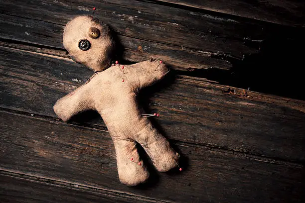 photo of creepy voodoo doll on wooden floor