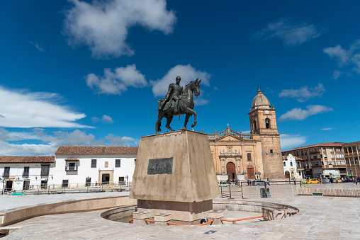 Monument of Simon Bolivar in the main square of the city of Tunja with a catholic church in the background. Boyaca. Colombia . May 24, 2019.