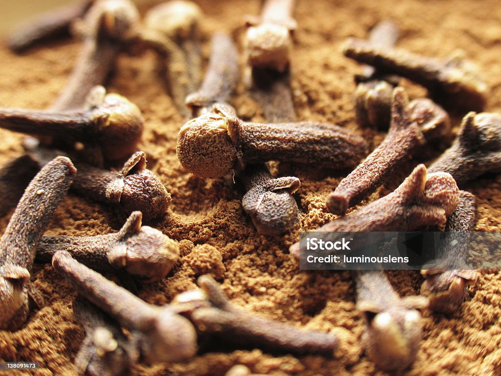 Cloves and Cinnamon Cloves lying atop cinnamon powder. Clove - Spice Stock Photo