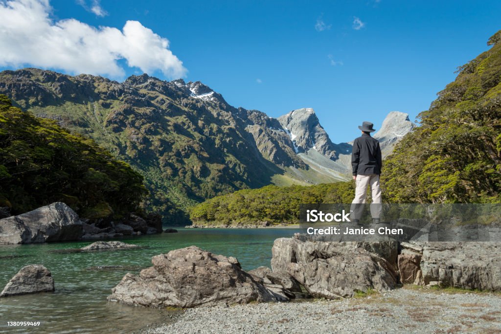 A man standing on the rocks by Lake Mackenzie on Routeburn Track, one of the great walks of New Zealand New Zealand Stock Photo