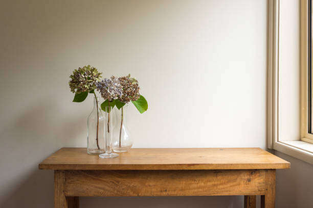 istock Dried hydrangrea flowers in glass vases on oak side table next to window 1380965552