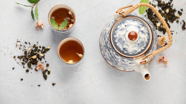 istock Asian teapot with herbal tea on light background. 1380969158