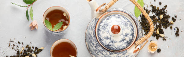 istock Asian teapot with herbal tea on light background. 1380969289