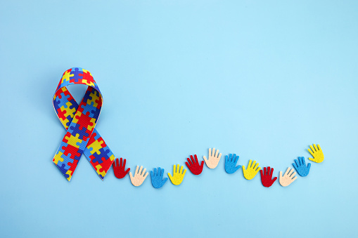Concepto de conciencia del autismo con manos coloridas sobre fondo azul. Vista superior photo