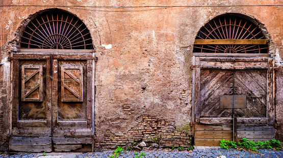 Old closed italian traditional wooden door against an old brick wall with arched opening - Tuscany - Italy