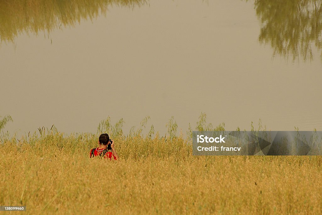 Photographer has reached the fish pond in Tuscany. A photographer is taking pictures of reflection on the Tuscany wheat fields on the sunny day. Camera - Photographic Equipment Stock Photo
