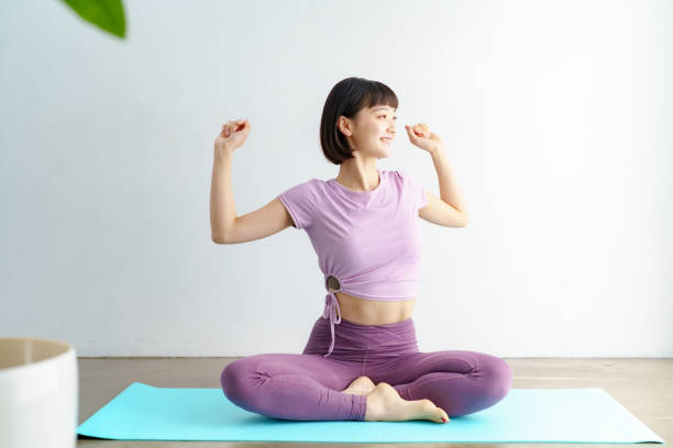 a woman taking a deep breath between yoga - stretching women attractive female indoors imagens e fotografias de stock