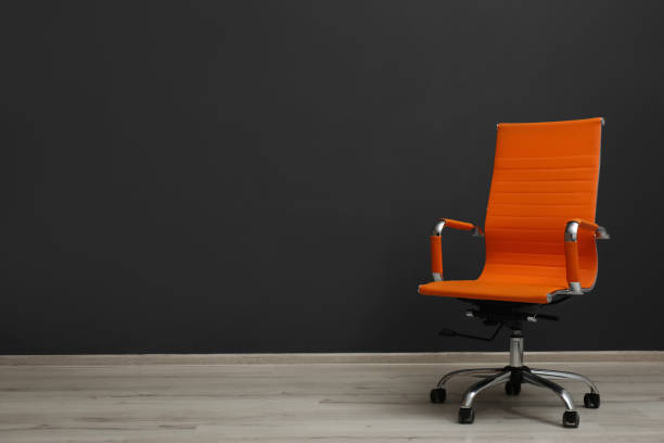 istock Comfortable office chair near black wall indoors. Space for text 1381038073