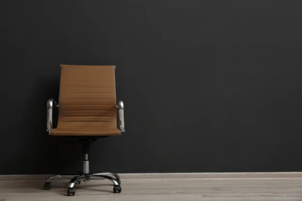 Comfortable office chair near black wall indoors. Space for text Comfortable office chair near black wall indoors. Space for text office chair stock pictures, royalty-free photos & images