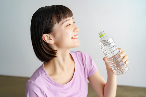 Asian young woman hydrating in sportswear indoors