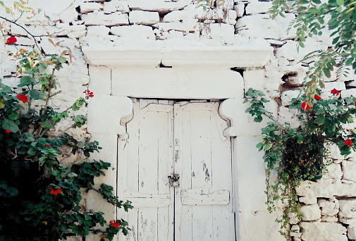 Old weathered door on a whitewashed stone wall of an abandoned house, Folegandros, Cyclades islands, Greece (Painting effects)