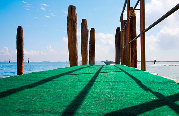Luxury  pier at dawn with green carpet and a yacht on the end. Cross processed colors.