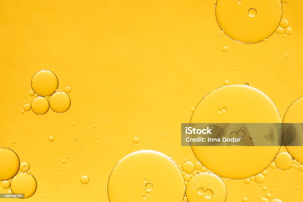 Golden yellow abstract oil bubbles or face serum background. Golden yellow abstract oil bubbles or face serum background. Oil and water bubbles macro photography. Cooking Oil Stock Photo