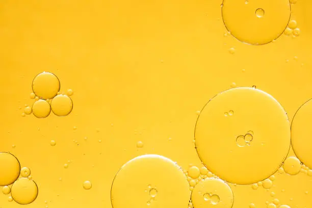 Photo of Golden yellow abstract oil bubbles or face serum background.