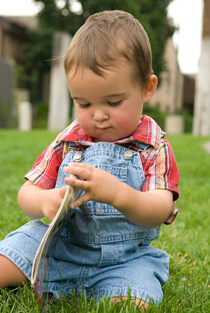 Young Boy niño leyendo un libro al aire libre en un parque - foto de stock