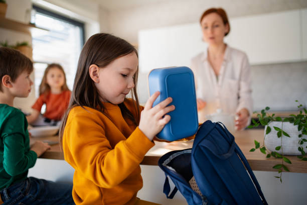 little girl packing lunch box to backpack in kitchen at home. - lunch box imagens e fotografias de stock