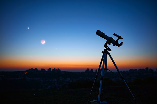 Telescopio astronómico bajo un cielo crepuscular listo para observar las estrellas. photo