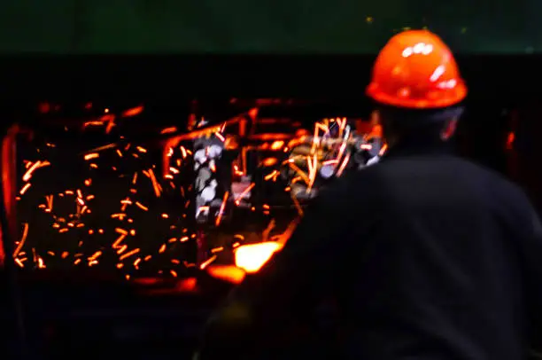 Blacksmith work with red hot iron under a press on metallurgical plant. Metal forging, stamping under hammer forge at workshop of forge factory. Blacksmithing, steelmaking and hot rolling mill.