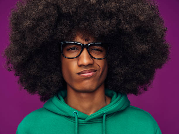 Portrait  of very angry man with handlebar mustaches and afro hair. He is wearing an orange t-shirt. Shot in studio on white background.