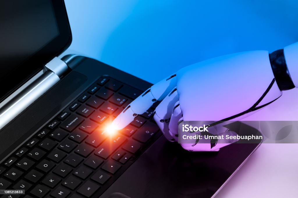 The robot's hand indicates that the enter key on the labtop computer's keyboard should be pressed. The concept is based on the internet of things and artificial intelligence robotics. Learning Stock Photo