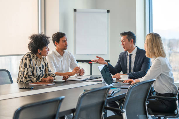 A Japanese Businessman Addressing Colleagues At A Corporate Business Meeting Successful Japanese business manager talking during a corporate meeting with his business partners. 1354 stock pictures, royalty-free photos & images