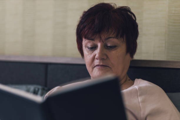 istock Senior woman reading a book in bed 1381253410