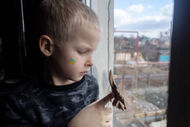 istock Child sits on the window and holding a fighter toy plane 1381263180