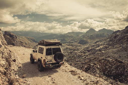 Off road 4x4 car on a high mountain pass, with mountains and cloudscapes in the background.