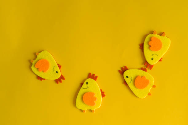 Four yellow felt decorative chickens arranged in a semicircle on a yellow background. Minimal concept, cute Easter card with a copy of the place for the text.