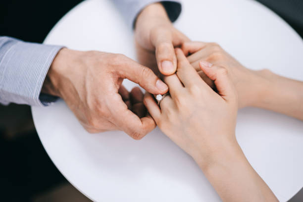 directly above, cropped shot of man putting an engagement ring onto woman's finger. romance and love concept - wedding anticipation togetherness wedding ring imagens e fotografias de stock