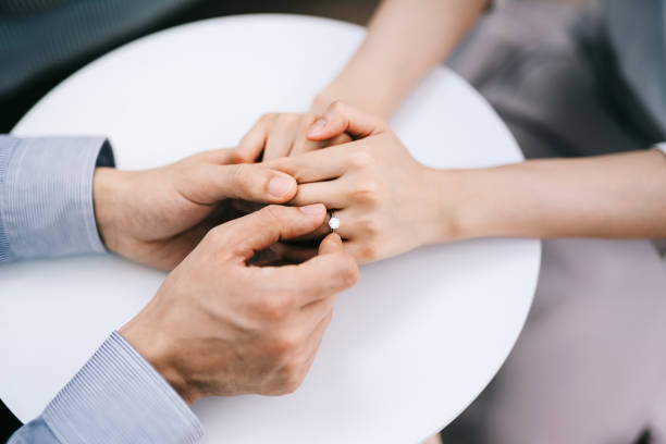 directly above, cropped shot of man putting an engagement ring onto woman's finger. romance and love concept - wedding anticipation togetherness wedding ring imagens e fotografias de stock